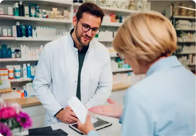 Farmacéutico asesorando a una cliente en el mostrador del punto de venta para farmacia